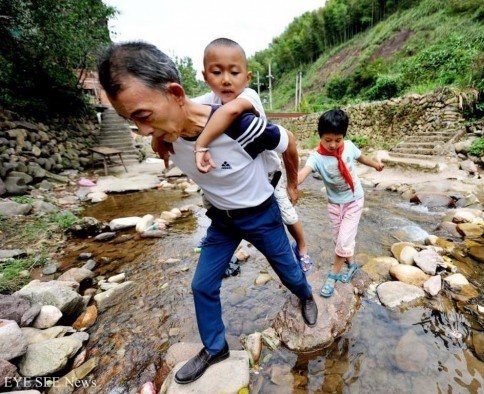 身兼校長及老師的祝雲漢每週要跨過小河到山口接孩子們上課。（圖：網絡照） 