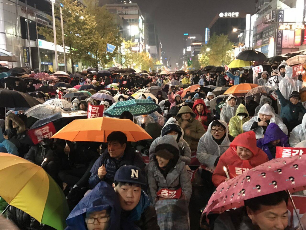 細雨紛飛的廣場上,民眾或站或坐,站立在兩旁的民眾約為席地而坐的3倍之多。圖/Lee Ji Eun