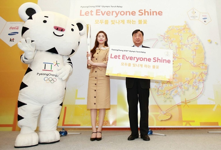 平昌冬奧組委會委員長李熙範 (右) 手持「Let Everyone Shine」口號看板、宣傳大使金妍兒舉起火炬象徵,背板為聖火繞行路線圖。圖/2018平昌冬季奧運會官網