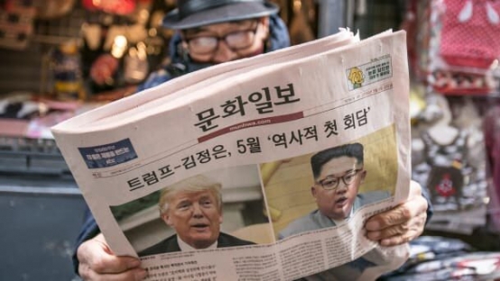 首爾街頭，一名長者正在閱讀3月9日的《文化日報》。頭版頭條寫道：川普 - 金正恩，5月「歷史性的首次會談」。 圖/彭博
